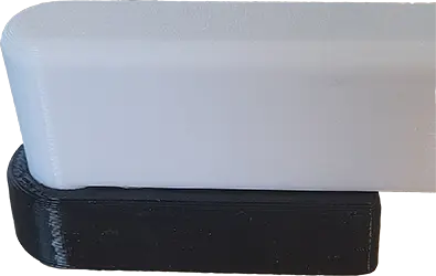 Nojatuolin jalkatassu (musta). Tulostettu kumimaisesta TPU 95A materiaalista, tassun toiminnallisuutta testattu nojatuolin jalkaa vastaavalla kappaleella (valkea).